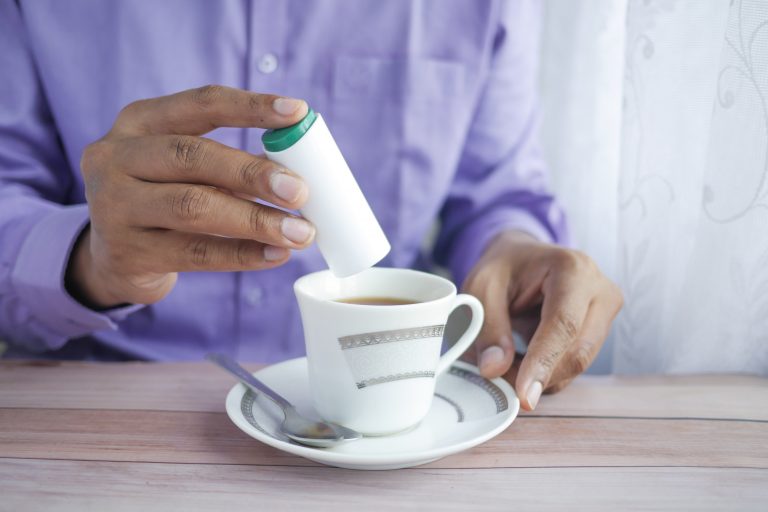 Man pouring artificial sweetener into a cup of tea.